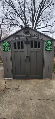 Customer's two Watercolor Marijuana Leaf flags decorating the front of a grey outdoor shed.