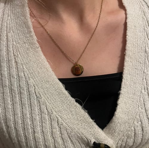 Customer wearing the gold-colored Družinsko Drevo necklace with its round family tree pendant.