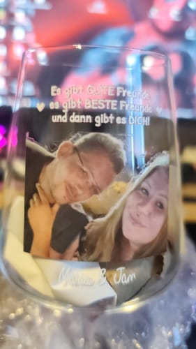 Kunde hält ein personalisiertes Weinglas mit einem Foto und einer Textgravur.