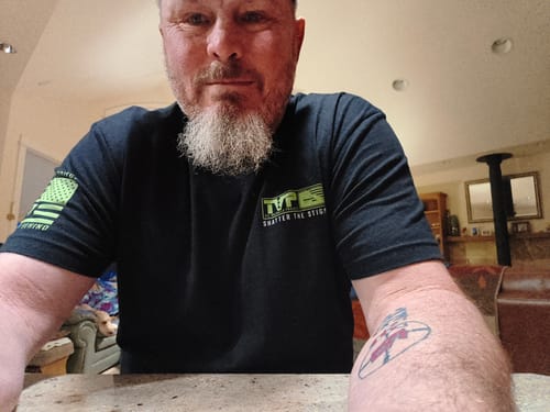 Reviewer wearing the black T.V.P. Elite Membership t-shirt, showing the logo on the chest and sleeve.