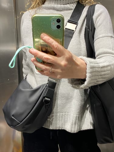 לקוחה עונדת את תיק הצד Valera Small השחור שלה בהצלבה.