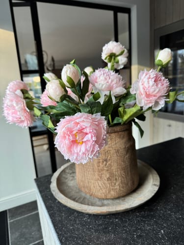 Recensent toont de roze Zijden Pioenrozen in een houten vaas op een aanrecht.