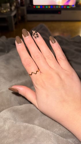 Ein Kunde trägt den eleganten, wellenförmigen Nalu Ring am Finger.