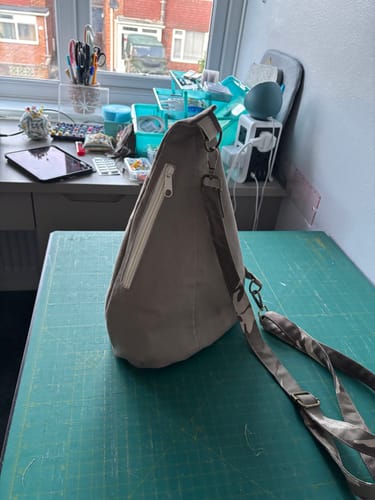 Reviewer's side view of a handmade beige bag with a strap made from the Camouflage Cotton Drill Fabric.