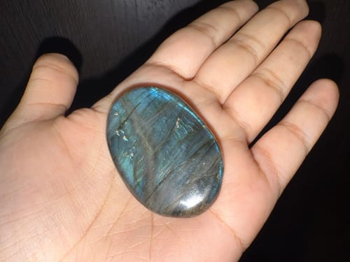 Customer holding a polished, iridescent monthly crystal in the palm of their hand.