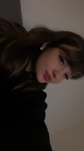 Nahaufnahme einer Kundin, die die langen, vollen Wimpern des PRETTY WOMEN STARTER KITs in einem schwach beleuchteten Raum zeigt.