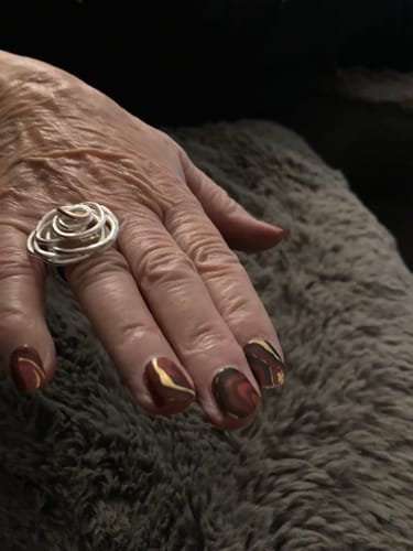 Kundin zeigt in einer Nahaufnahme ihre Nägel mit dem UV-Gel 'Golden Emerald Marble' in Marmor-Optik.