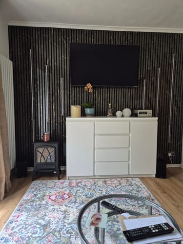 Customer's living room with the dark marble acoustic wall panels installed as a feature wall behind a TV.