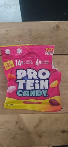 Un client présente le sachet de Protein Candy rose et jaune posé sur une surface en bois.