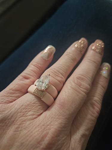 Reviewer's hand showing two pink Silicone Rings stacked, one with a large pear-cut stone.