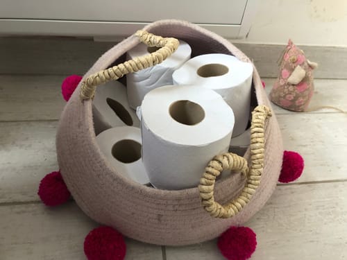 Photo d'un client montrant plusieurs rouleaux de papier toilette confort rangés dans un panier rose.