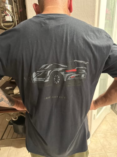 Reviewer from behind showing the car graphic on the back of the black DCG85 shirt.