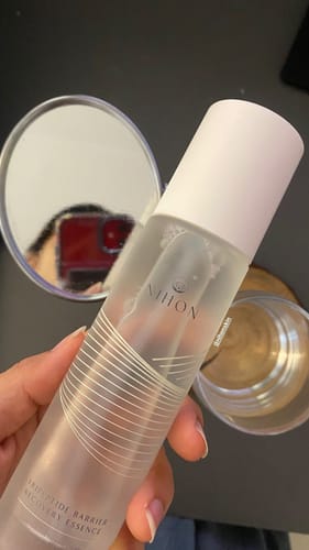 Close-up of a reviewer holding the translucent Tripeptide Barrier Recovery Essence bottle.