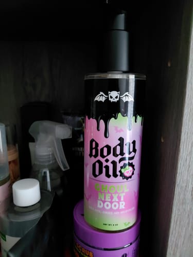 Customer's bottle of Ghoul Next Door Body Oil with a colorful, spooky-themed label, sitting on a shelf.