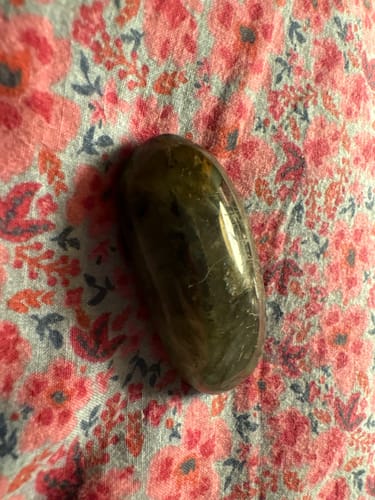 Customer's dark, oblong labradorite moonstone crystal resting on a floral fabric.