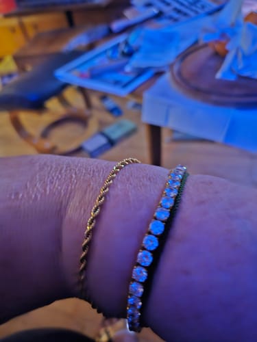 Close-up: Reviewer wearing the gold Clean Rope Bracelet on their wrist, stacked next to a jeweled bracelet.