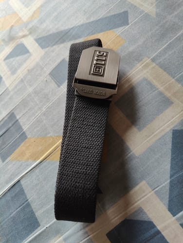 Customer's black 5.11 Tactical Belt with a large stainless steel buckle laid out on a patterned surface.