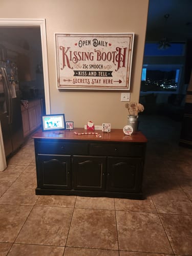 Customer's Vintage Rustic Kissing Booth sign hanging on a wall above a dark console table in their home.