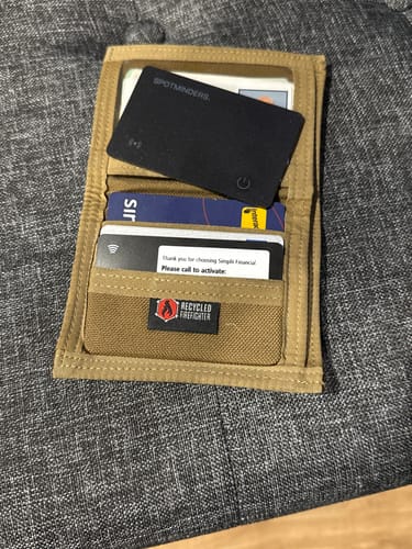 Customer's SPOTMINDERS Tracking Card fitting neatly into a slot in an open tan wallet.