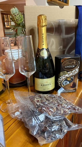 Customer's Celebrate A Good Life Gift Box with champagne, glasses, chocolate, and biltong arranged on a wooden table.