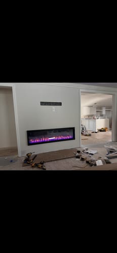 Customer's recessed Napoleon Entice Electric Fireplace with purple flames, installed in a wall during a home remodel.