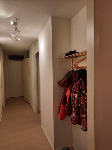 Klant toont de terra-kleurige Spinder Design Victorie kledinghangers die aan een kapstok in een hal hangen.