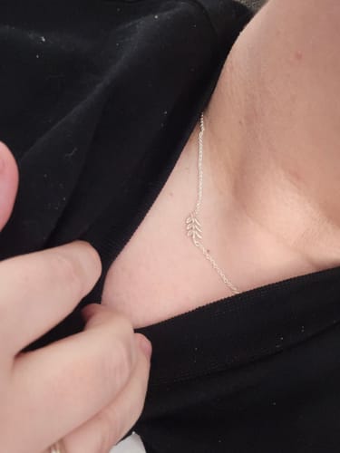 Close-up of a reviewer wearing the delicate silver Providence Necklace against their neck and a black shirt.