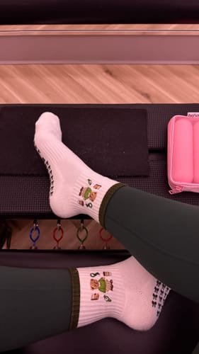 Customer wearing the cute Merry Beary grip socks with green leggings in a studio.