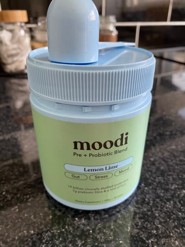 Customer's tub of moodi Pre + Probiotic Blend in Lemon Lime flavor, shown on a kitchen counter.