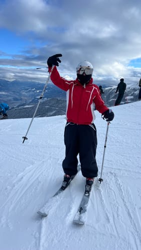 Reviewer on a snowy mountain wearing the baggy, dark waterproof snow pants while skiing.