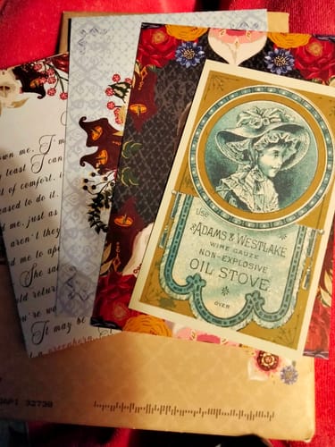 Customer's collection of Lily Clara Resend letters and decorative vintage cards fanned out on a red surface.