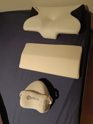 Avis d'un client : le coussin cervical Cellsius et deux autres coussins de soutien sur un lit.