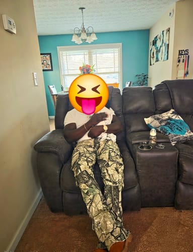Customer relaxing in a recliner wearing the stacked Vortex Cargo Denim in woodland camo.