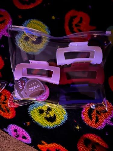 Customer's colorful Cloud Clips and stickers inside a clear zippered pouch on a patterned blanket.