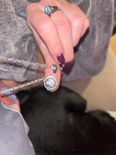 Close-up of a reviewer holding the silver UPGRADED BIPOLAR PENDANT on its chain.