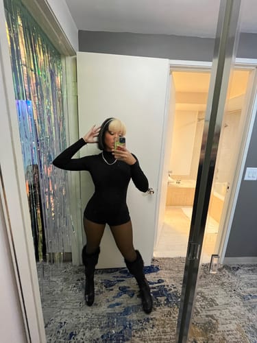 Reviewer taking a mirror selfie in the fitted black Crystal Turtleneck Romper.