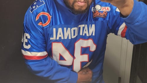 Customer taking a mirror selfie wearing the custom blue football jersey with a hoodie.