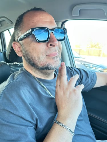 Cliente en un coche usando su Cadena Cuban Link plateada y una pulsera a juego.