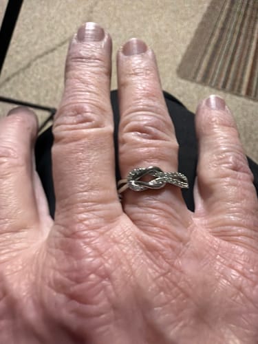 A close-up of a reviewer's hand wearing the silver Soul Sisters Knot Ring on their finger.
