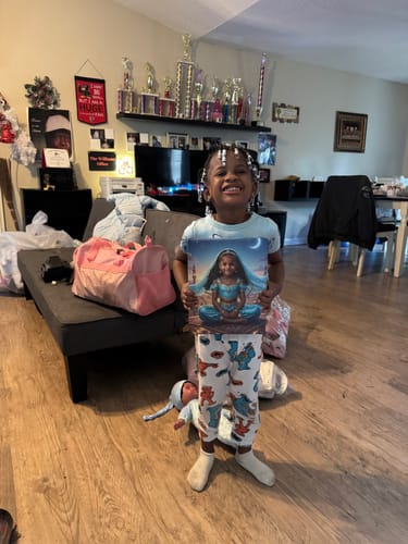 A happy young customer holds up her personalized 'The Greek Spartan' canvas in her living room.