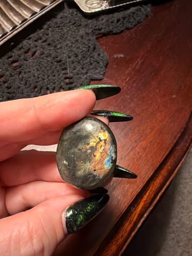 Customer holding a smooth, dark labradorite moonstone with colorful flashes.
