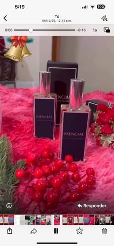 Cliente muestra dos frascos del perfume ESENCIAL sobre una superficie rosa con adornos festivos.