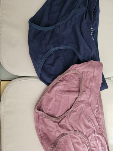 Customer's navy and dusty pink Mère Bottoms with a V-shaped front, laid out on a cushion.