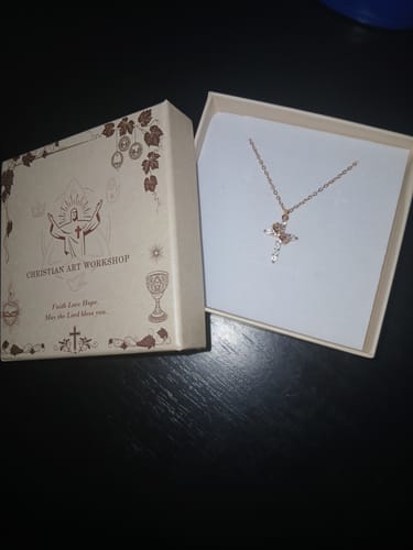 Reviewer's rose gold Crowned in Faith Cross Necklace presented in its decorative gift box on a dark surface.
