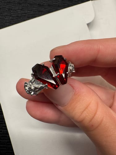 Customer holding the intricate PROMISE RING, showing its two red, coffin-shaped stones forming a heart.