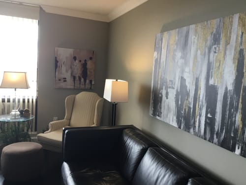 Customer's 'Abstract People' canvas hanging on a living room wall above a wingback chair.