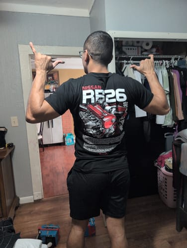 Reviewer from behind wearing the black TWIN-TURBO TEE, showing the Nissan RB26 engine graphic on the back.