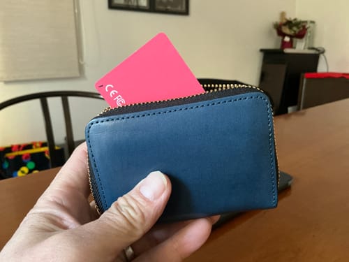 Customer holding a blue wallet with the pink SPOTMINDERS Tracking Card placed inside.