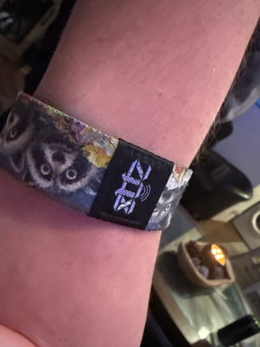 Close-up of a customer's wrist wearing a patterned Trash Pandas Collection wristband with raccoon faces.