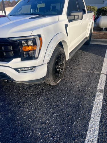 Customer's close-up of a white Ford F150 front wheel, pushed out to align with the fender after installing the wheel spacers.